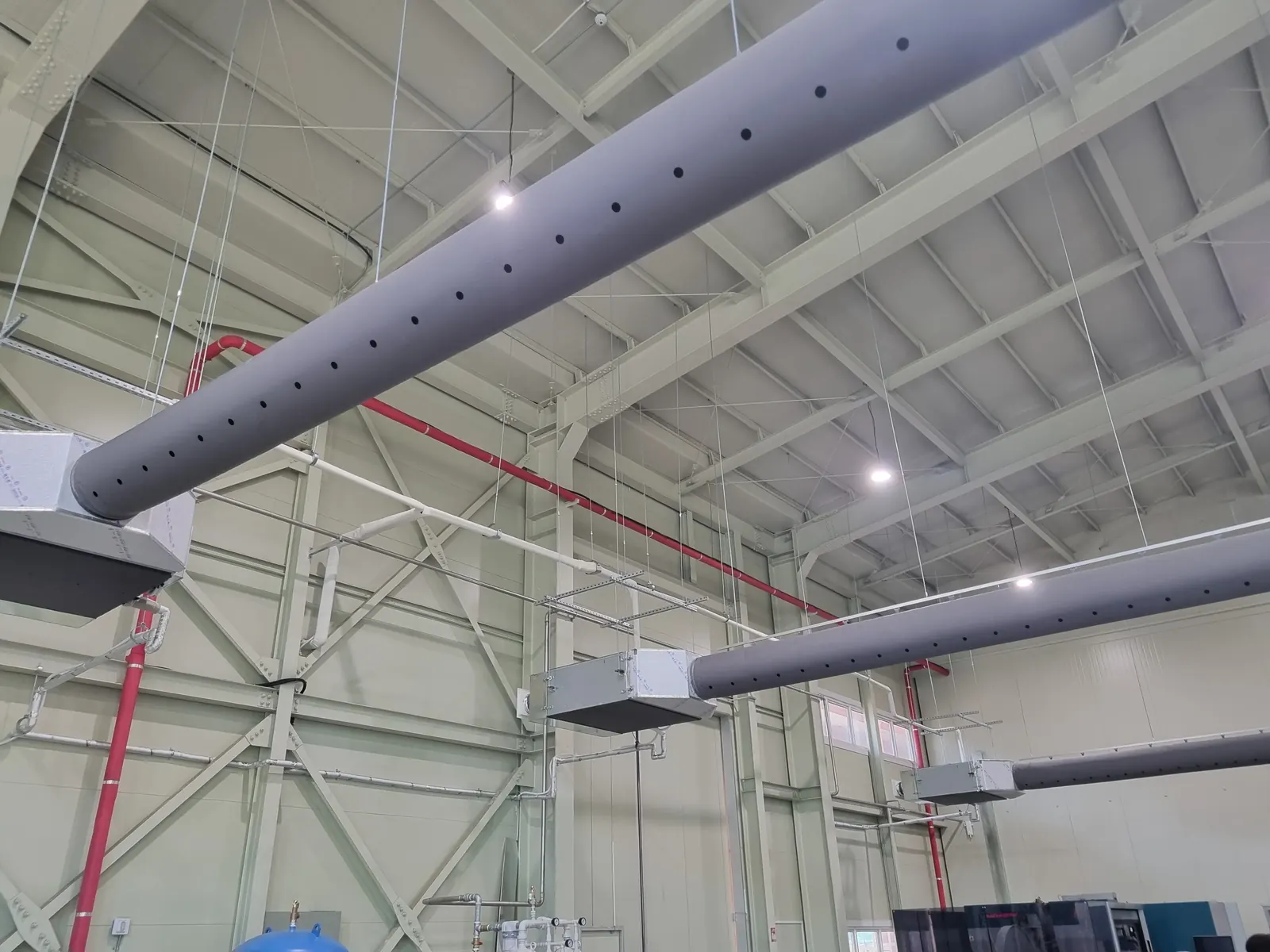 Two long grey round fabric ducts suspended from the roof of a high-bay warehouse